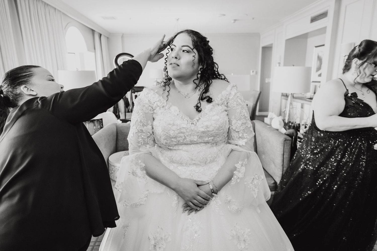 Black and white photo of wedding preparation with final makeup touches.