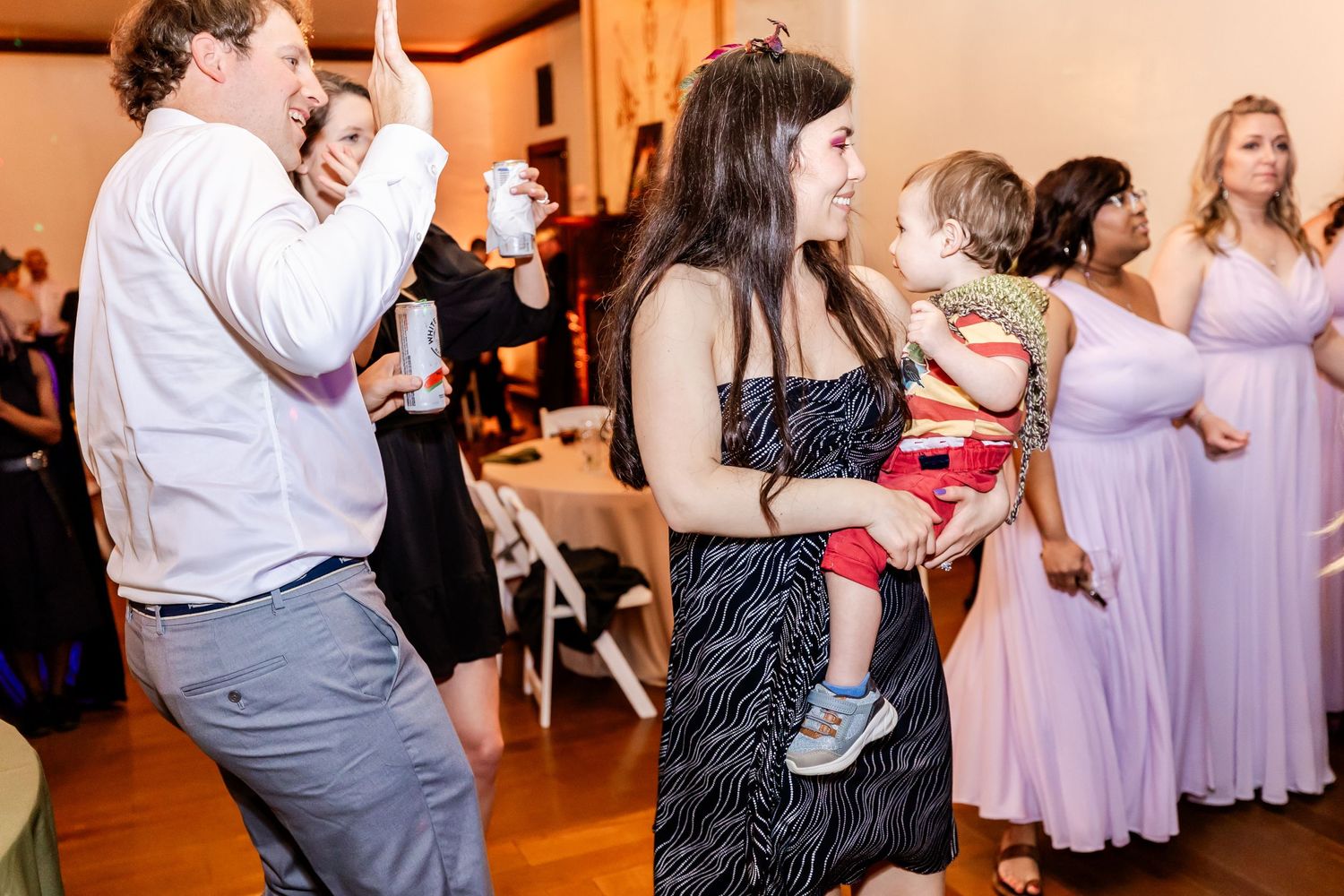 Celebration on a dance floor with guests in formal wear and casual attire mingling together.
