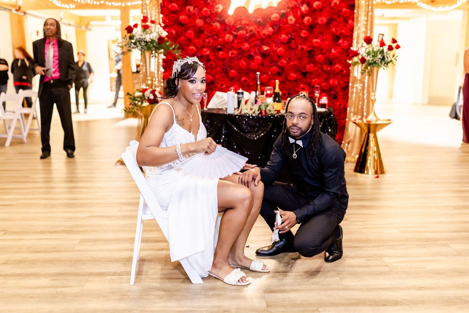 Wedding reception scene with red balloon wall backdrop and couple interacting.