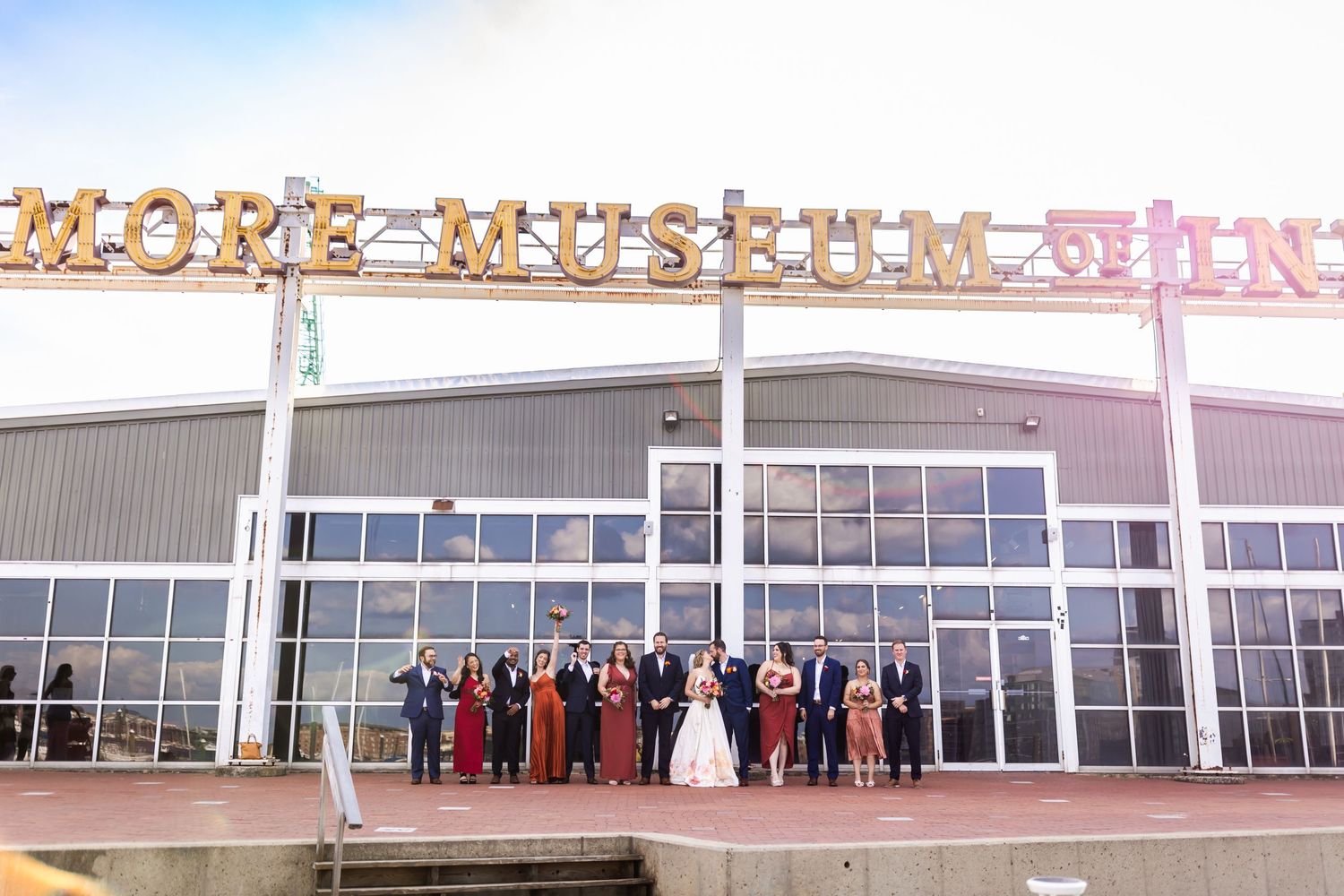 A wedding party poses for a photo outside More Museum Store beneath large signage on a modern building facade.