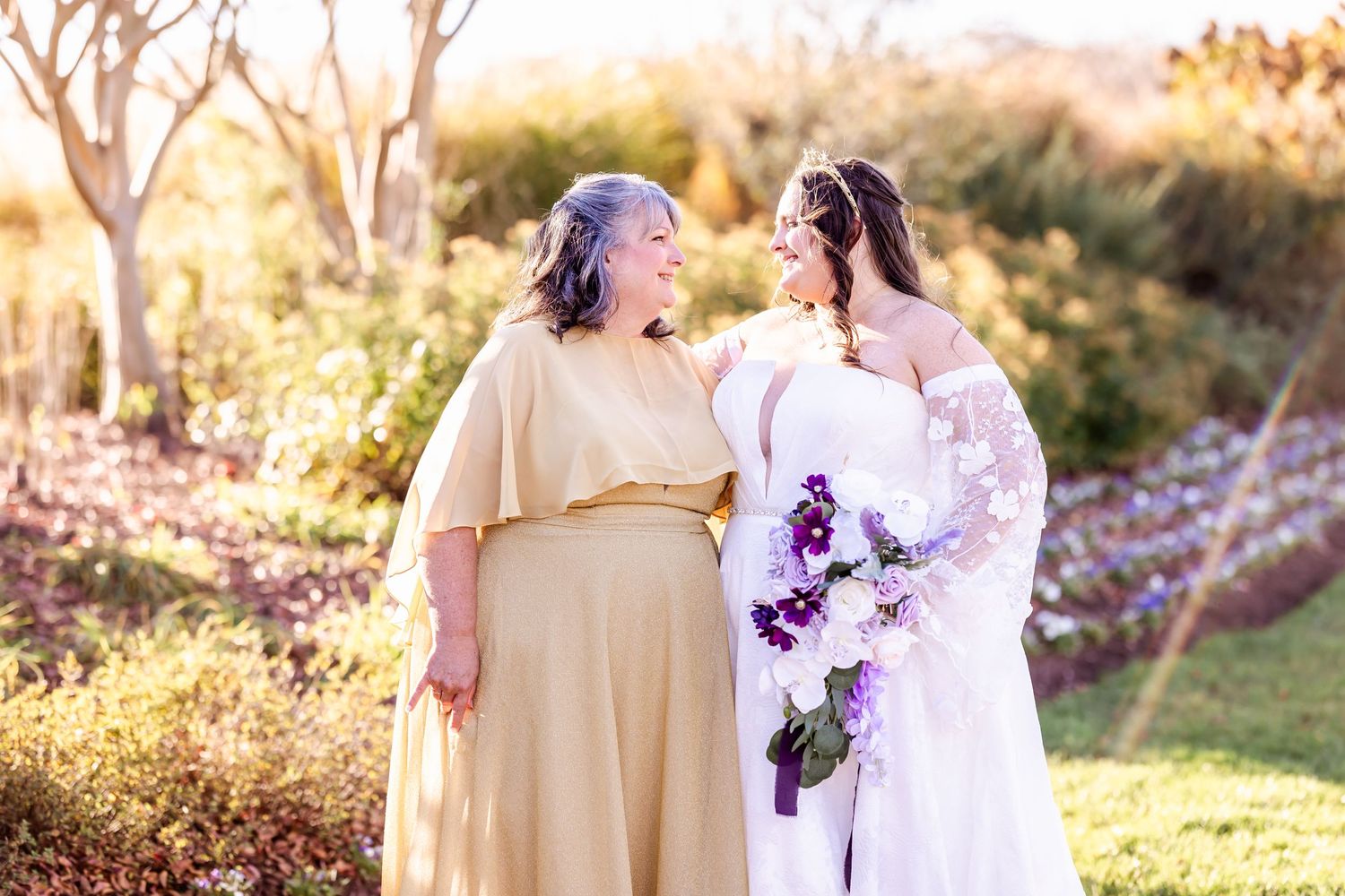Two people share a joyful moment together in a garden setting at sunset.