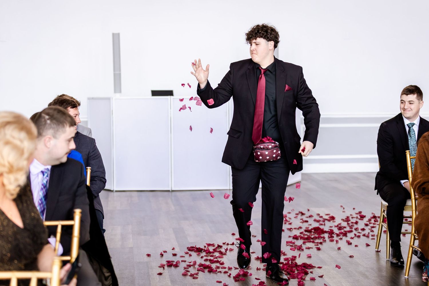 People celebrating with rose petals scattered across a bright indoor venue floor.