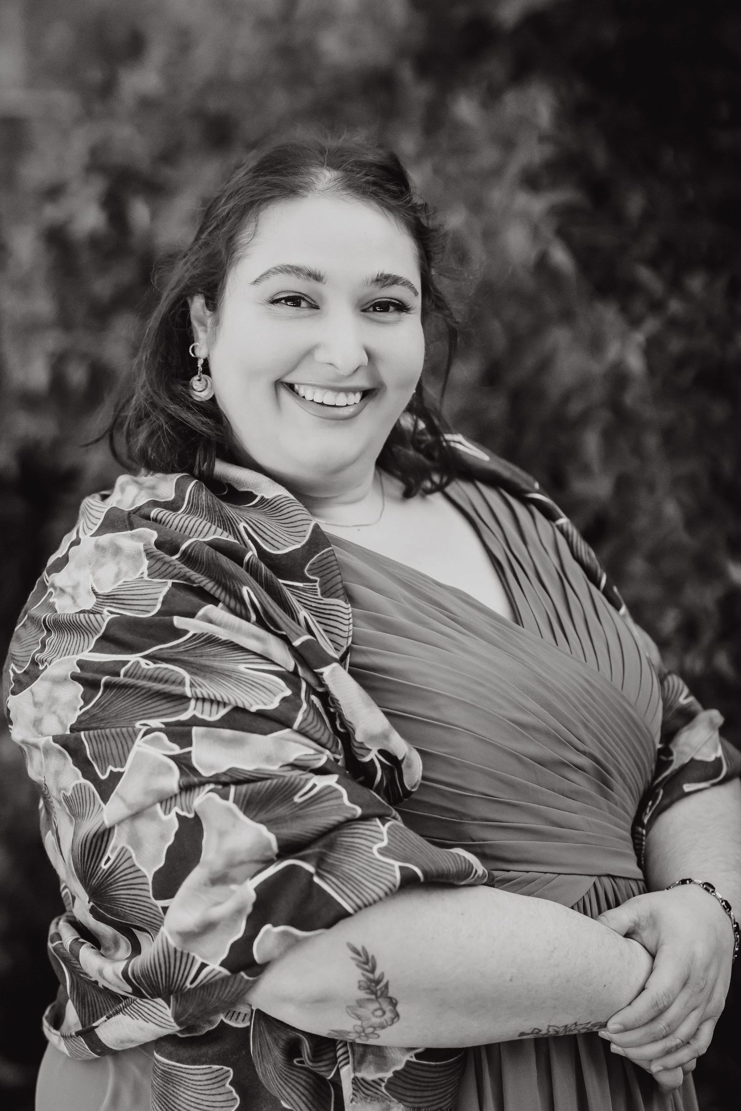 A black and white portrait of someone wearing a floral patterned wrap dress outdoors.