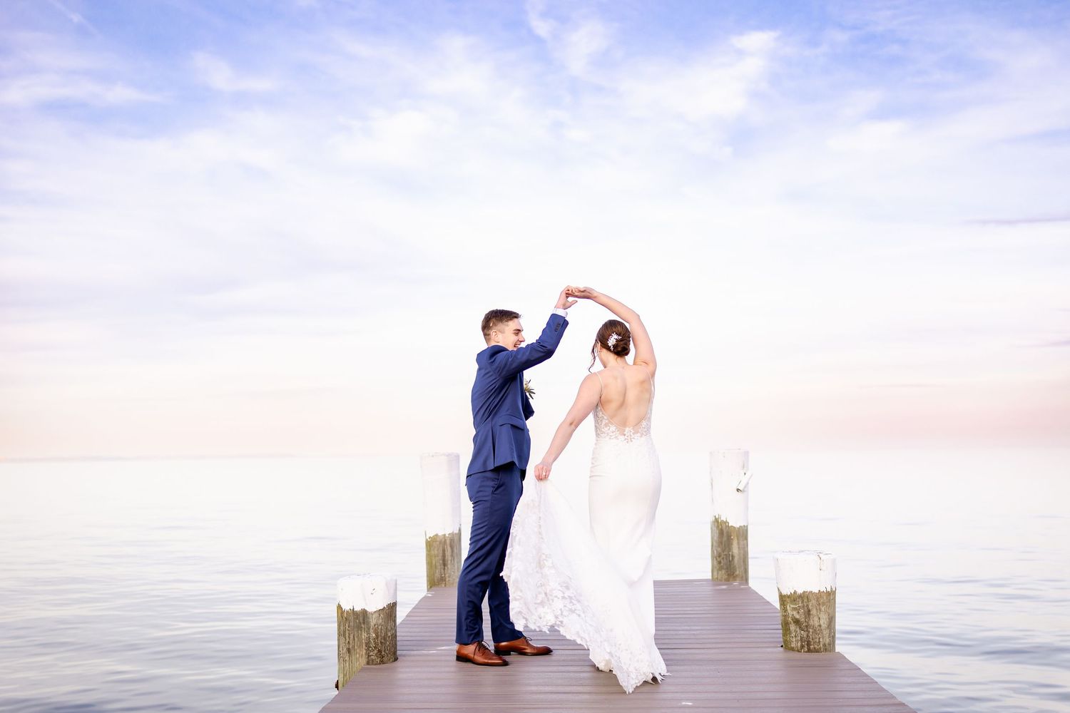 Couple shares romantic moment on wooden pier overlooking serene water during sunset.