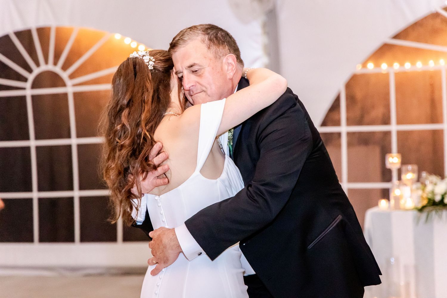 A romantic moment between newlyweds dancing under string lights at their reception.