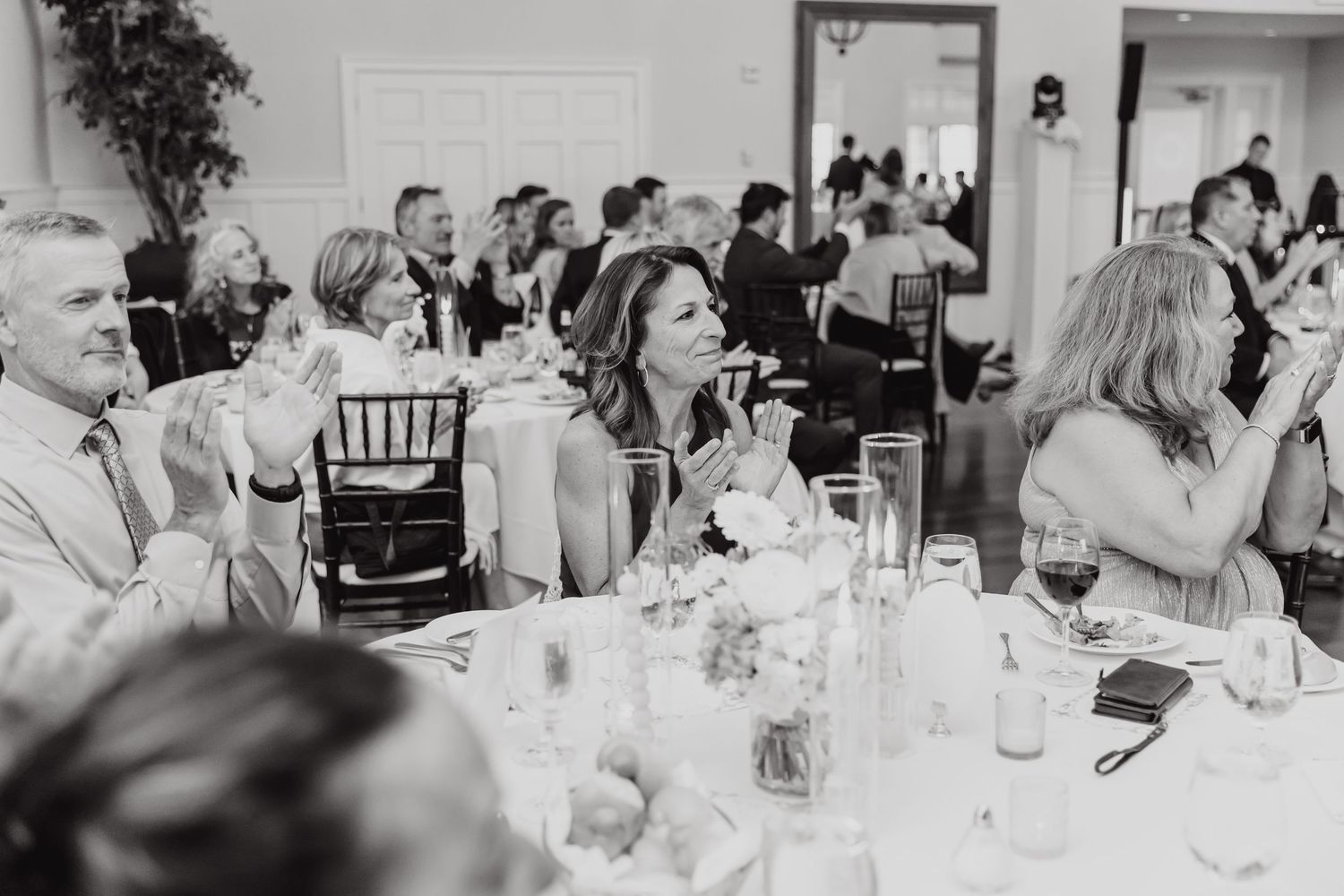 Wedding reception guests seated at tables engaging in lively conversation.