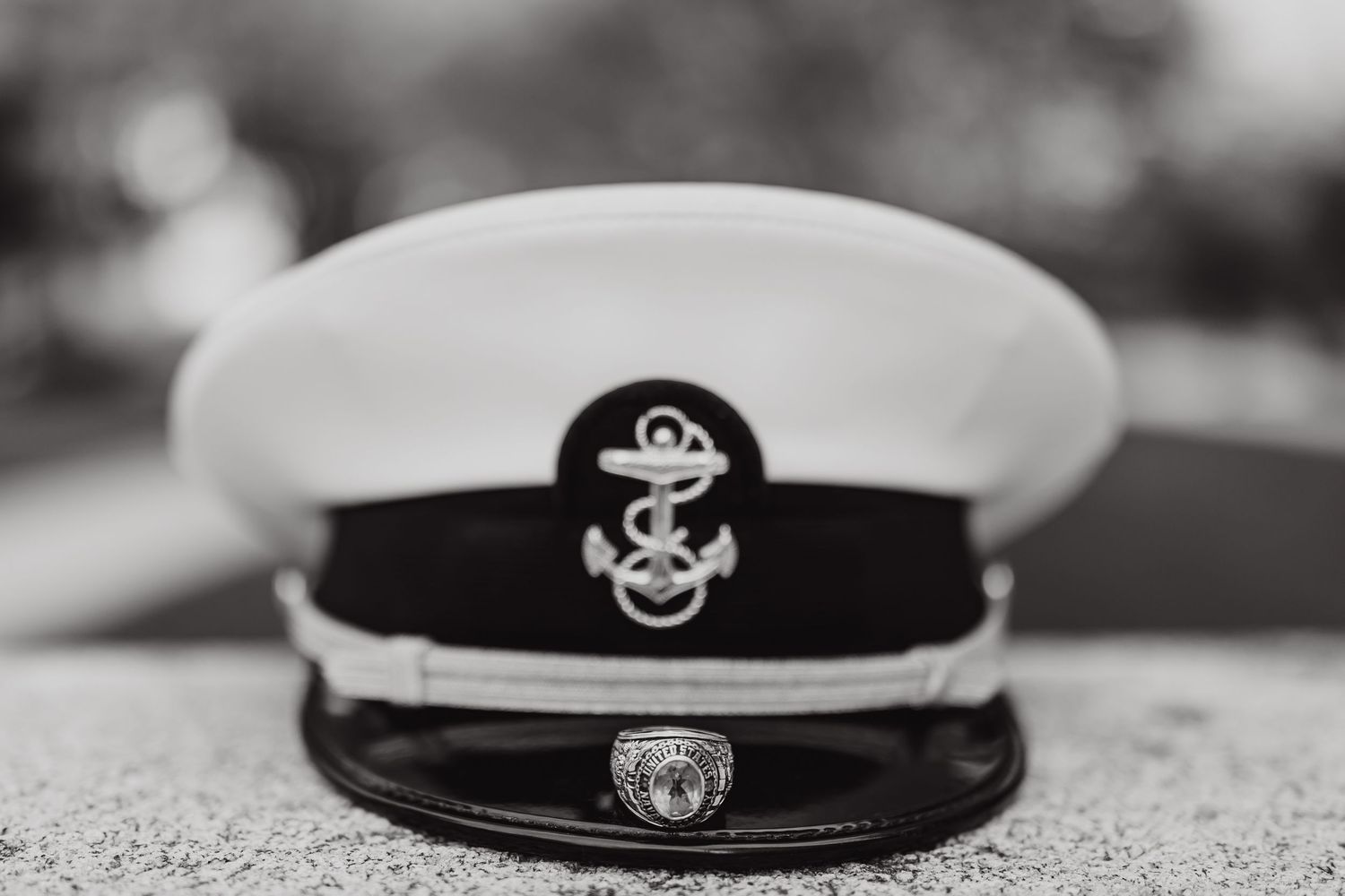 Navy officer's dress cap with anchor emblem shown in black and white photography.