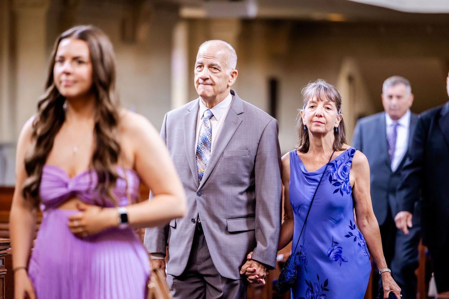 Wedding guests in purple and blue dresses walk through an outdoor venue.