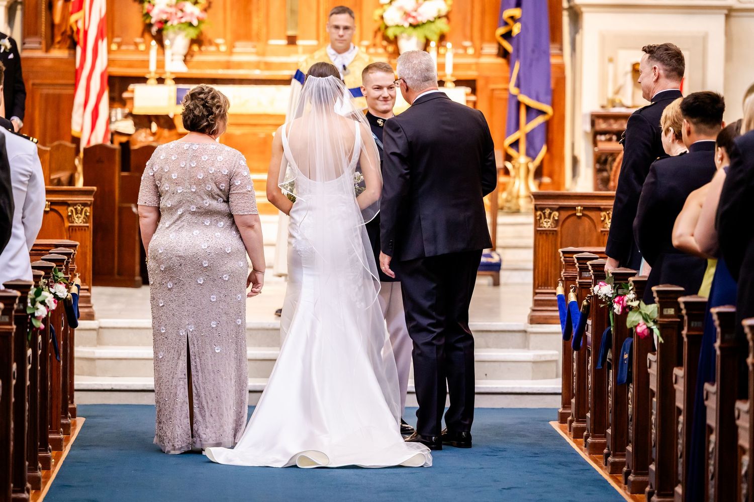 Wedding ceremony in progress inside a grand church with wooden pews and decorative details.