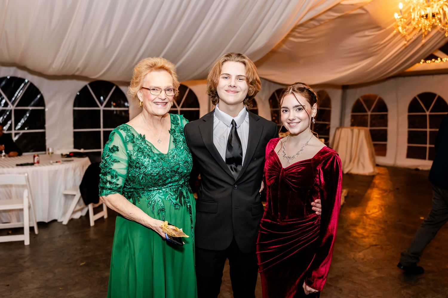 Wedding reception guests in formal attire mingling in an elegantly lit indoor venue.