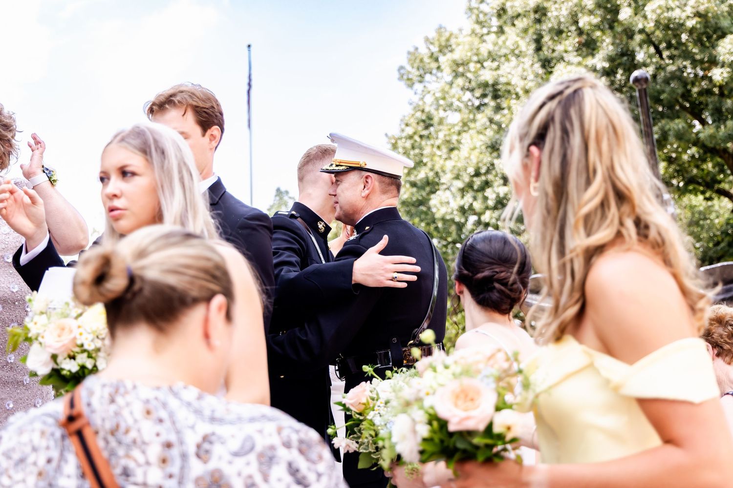 Wedding guests celebrate outdoors during a sunny garden reception.