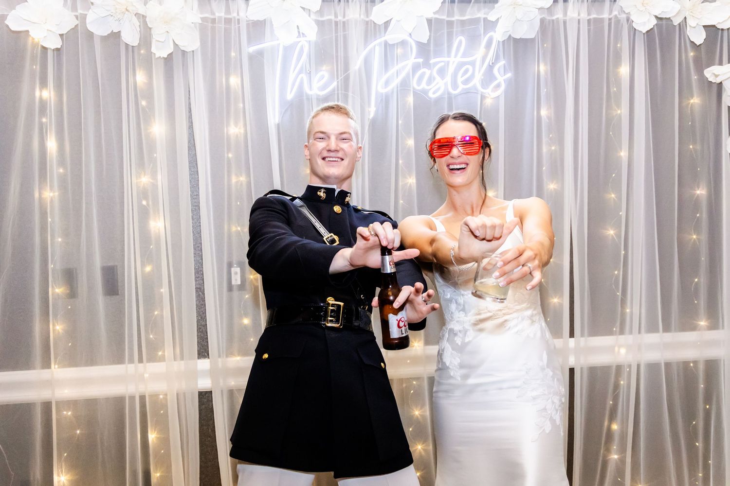 Wedding reception dance party with guests celebrating under sparkling lights and sheer curtain backdrop.