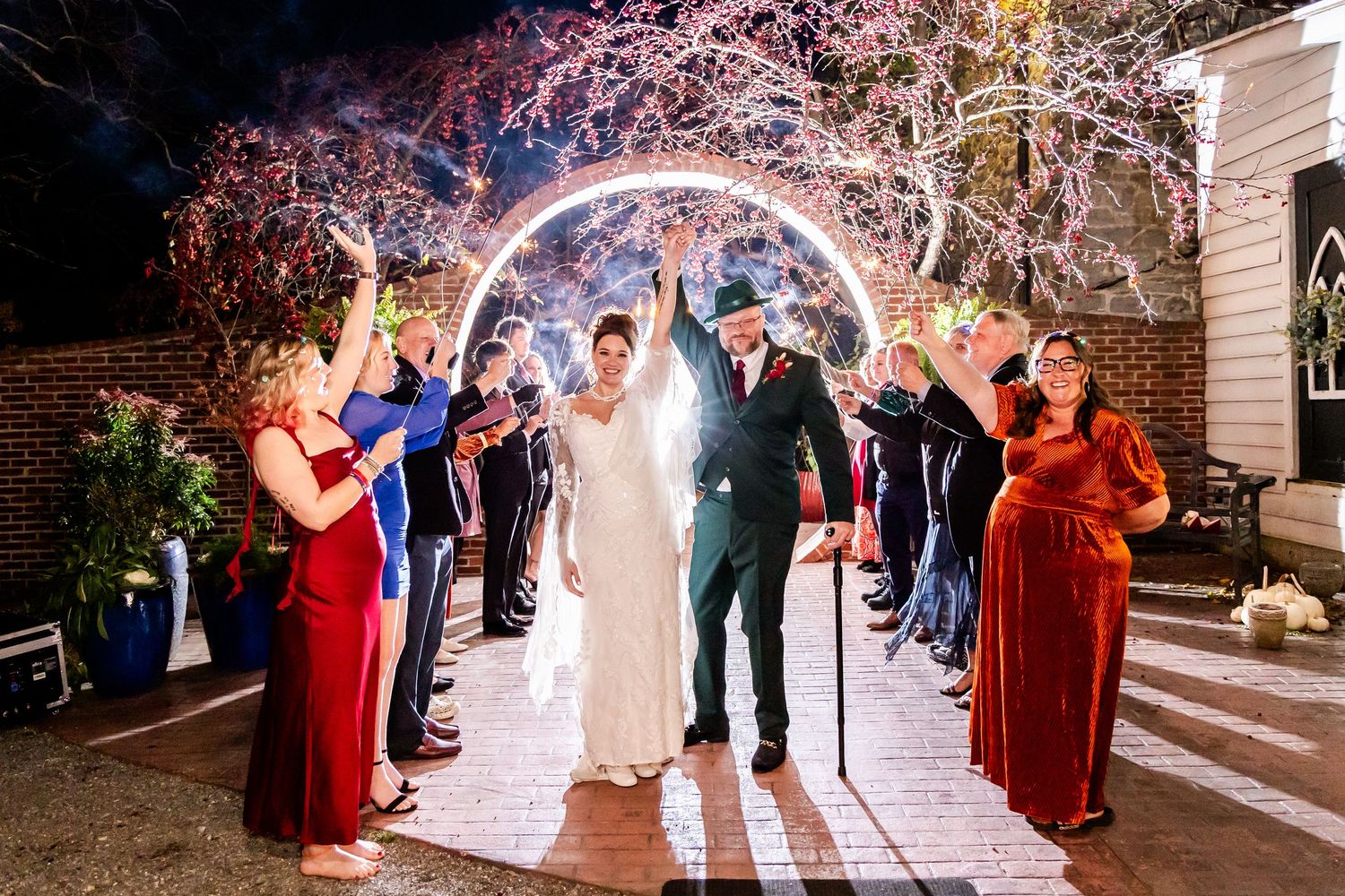 Wedding party celebrates with sparklers during an evening reception at an outdoor venue.
