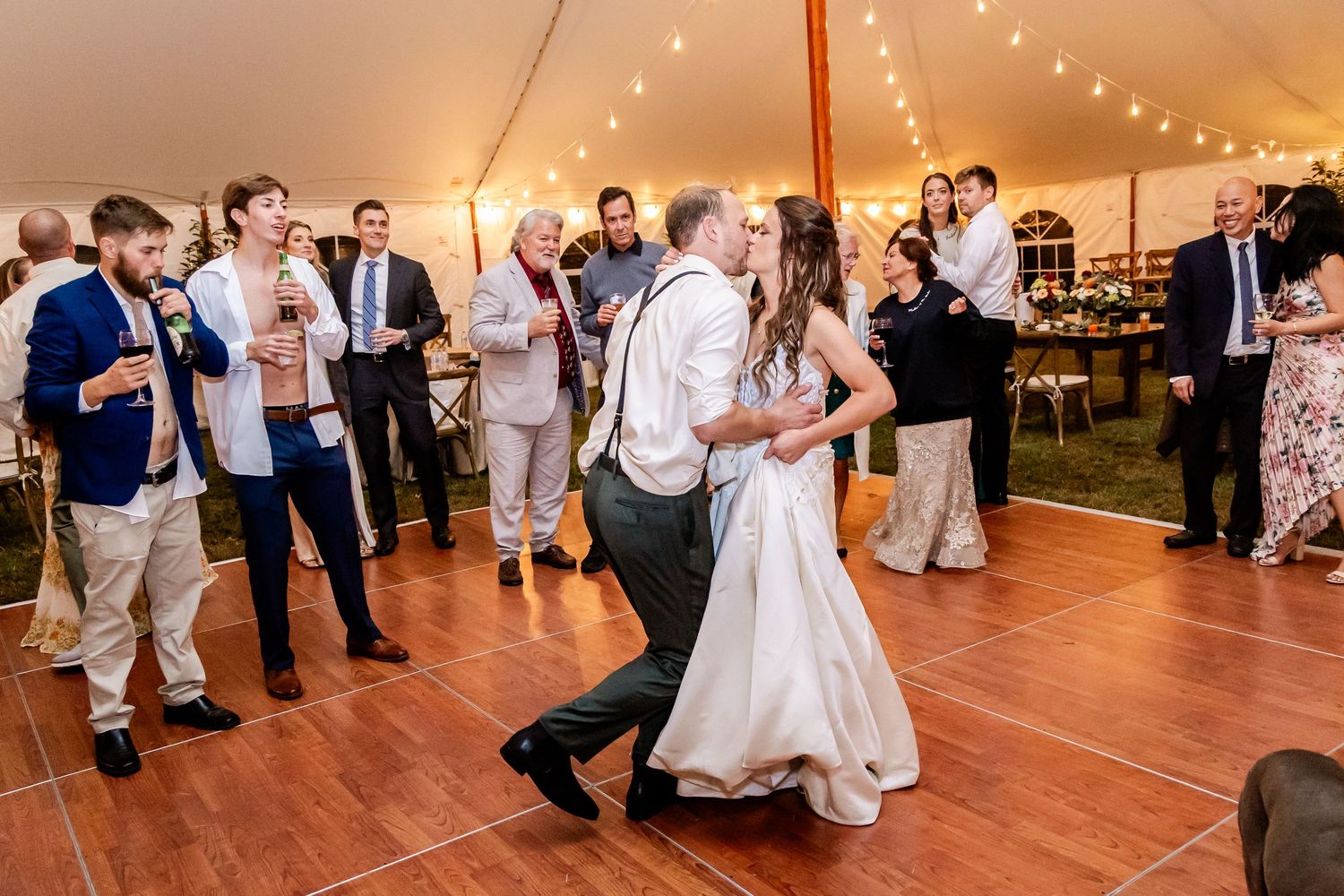 Couple dancing on wooden floor during wedding reception while guests watch.