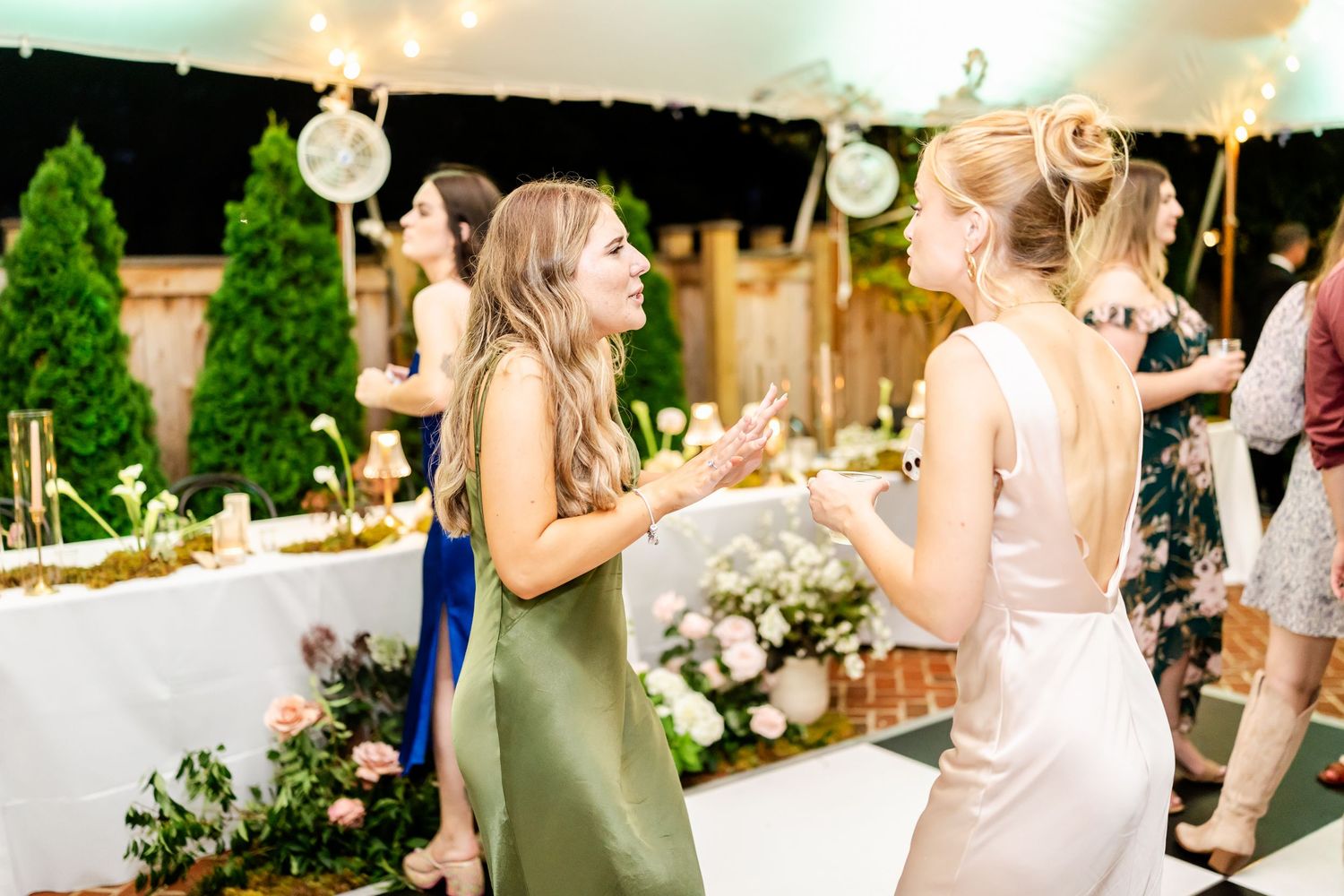 Wedding reception party outdoors at sunset with string lights and dancing guests.