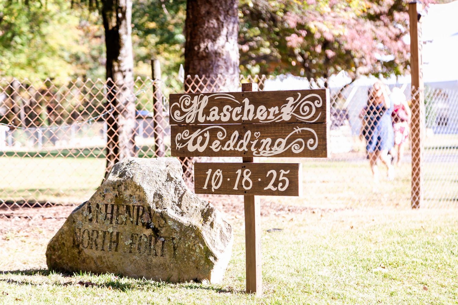 Decorative wedding date stones arranged on grass under trees.