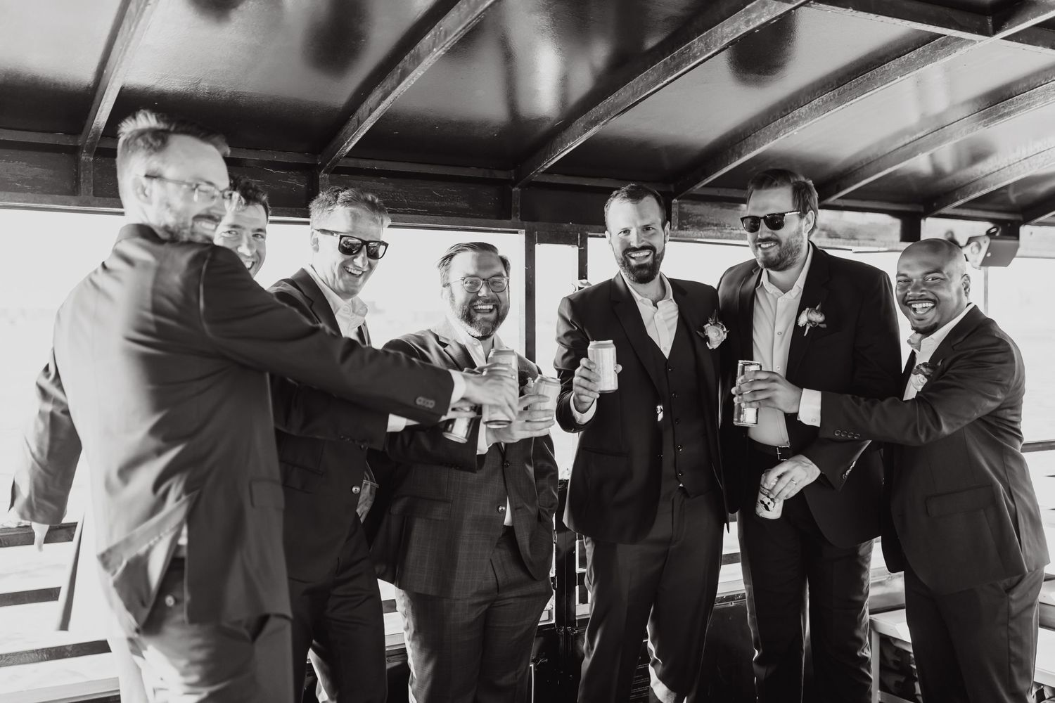 Vintage black and white photo of men in suits toasting drinks at a gathering.