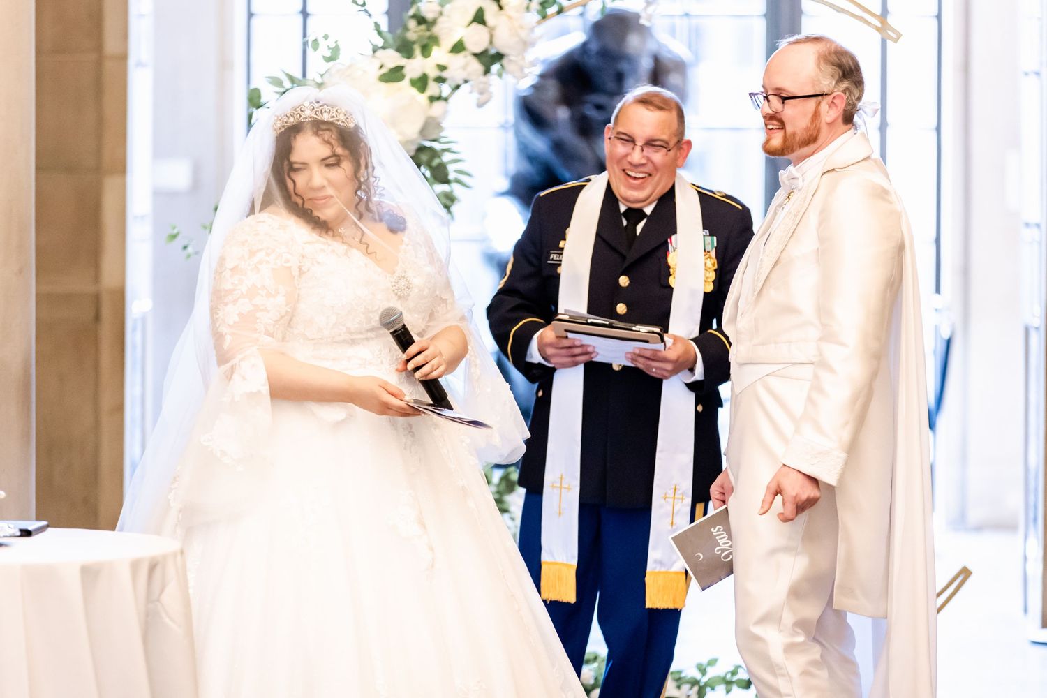 Wedding ceremony with couple and officiant in blue stole exchanging vows at decorated altar.