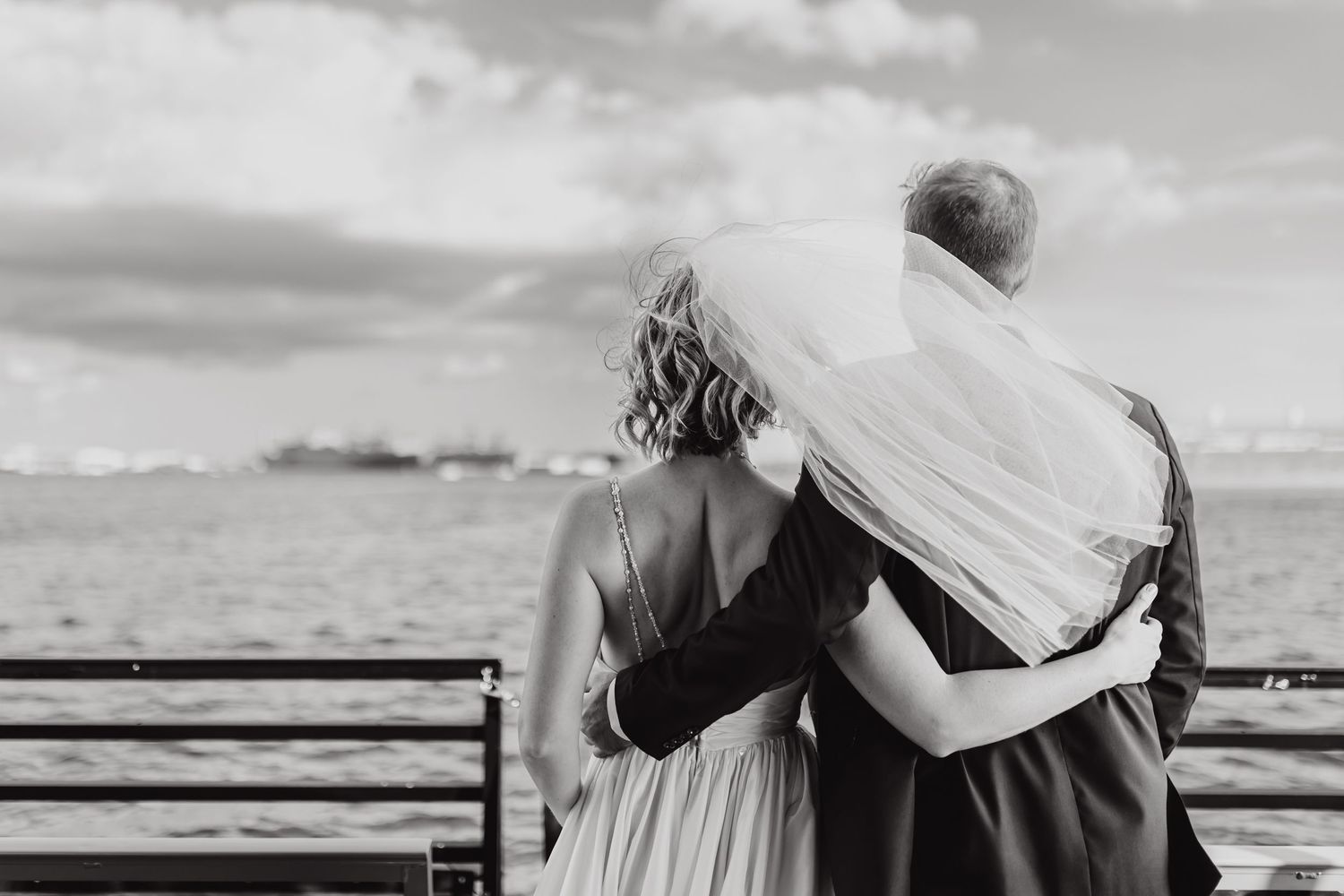 Black and white intimate moment captured between two people looking out over railing.