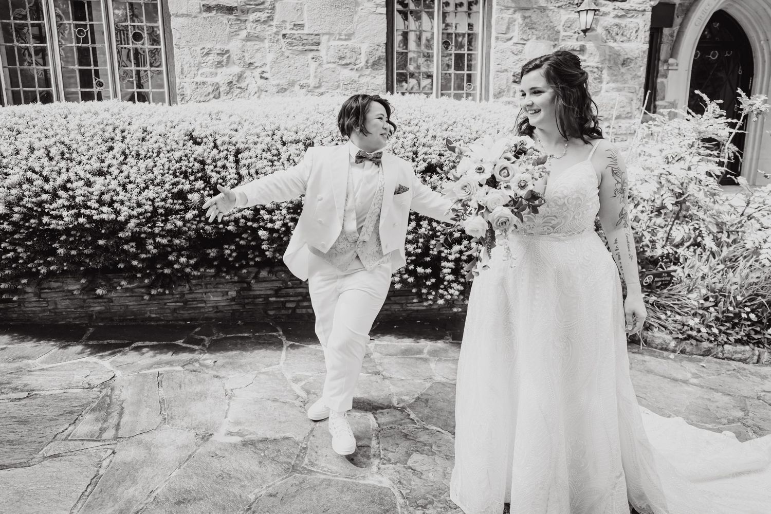 Black and white photo of wedding couple sharing joyful moment on stone patio.