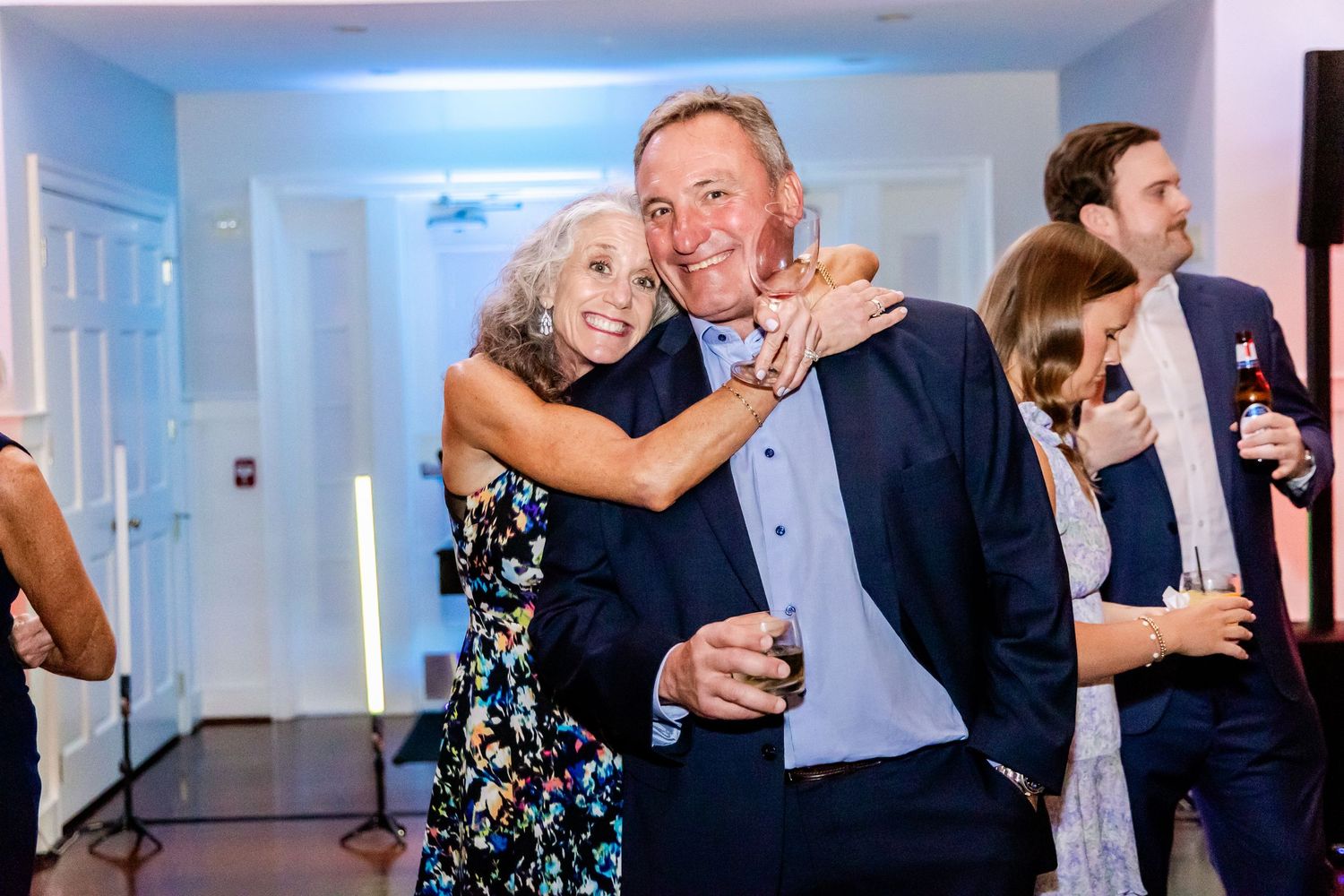 Wedding guests celebrate and dance together during a lively reception in an elegant white venue.