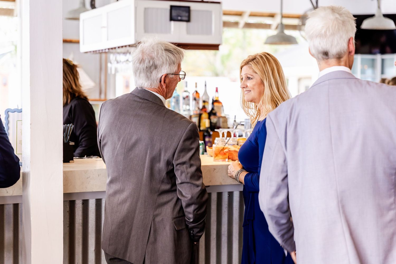 Wedding reception venue with guests mingling at tables in bright indoor setting.