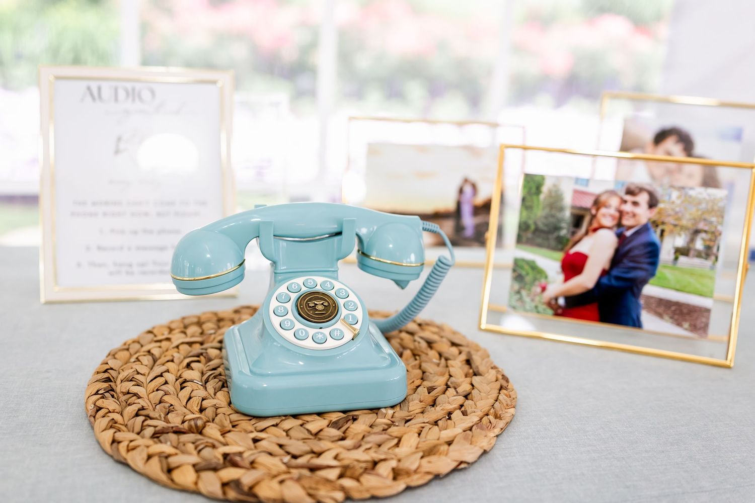 Vintage-style rotary phones in turquoise blue displayed on woven placemats with framed photos.