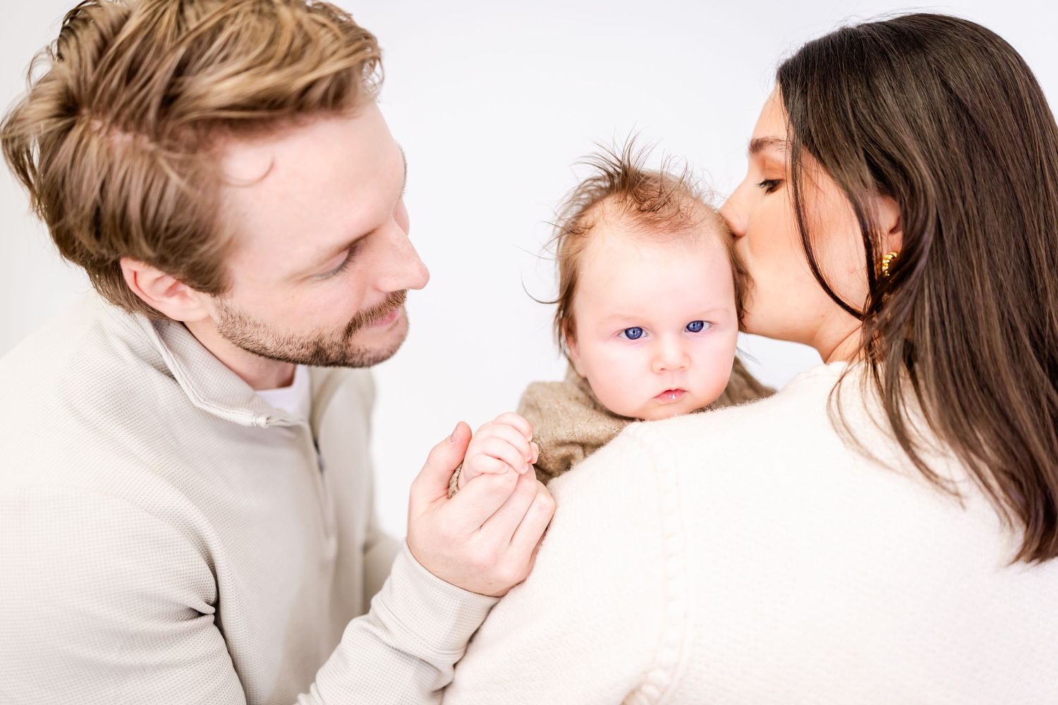 A family shares a tender moment together against a white background.
