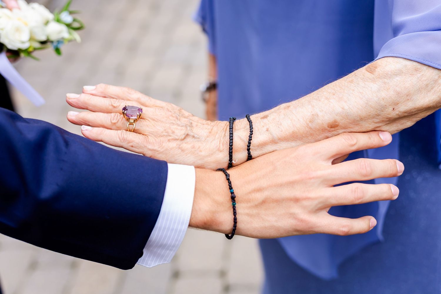 Close-up of hands during wedding ceremony with elegant blue attire details.
