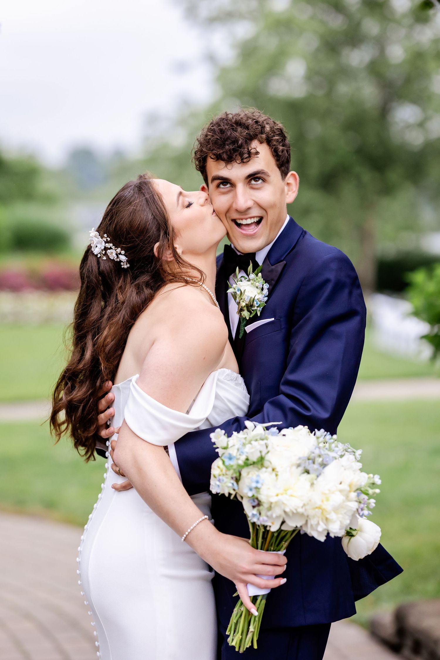Joyful wedding couple embracing and laughing together in an outdoor garden setting.