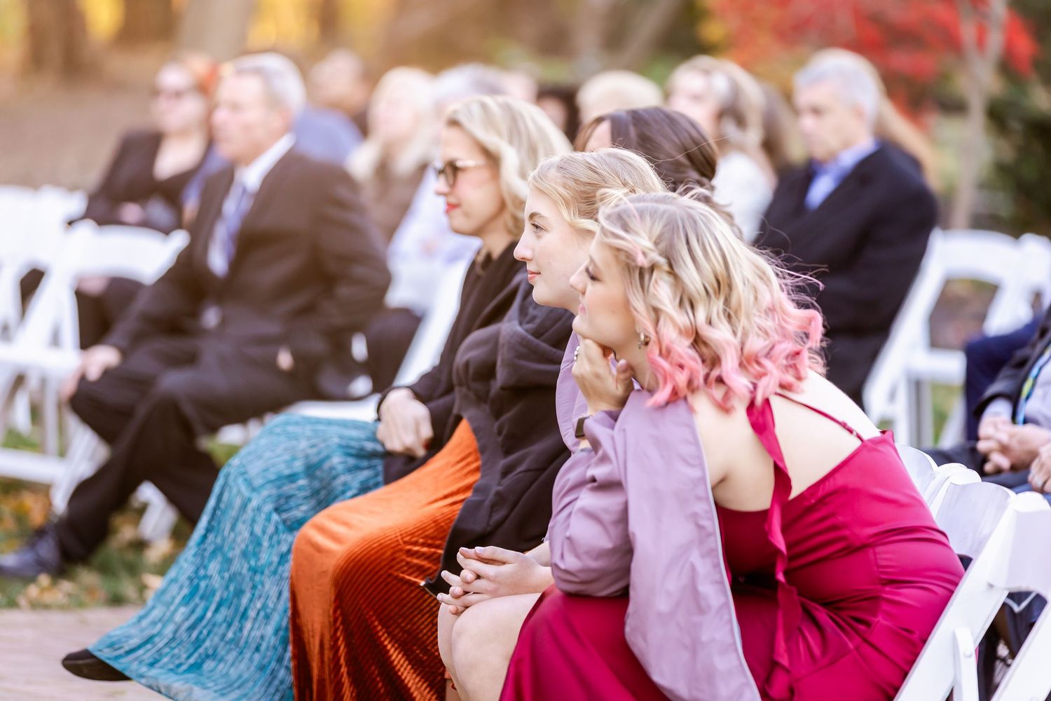 Wedding guests seated outdoors watching ceremony during autumn season.