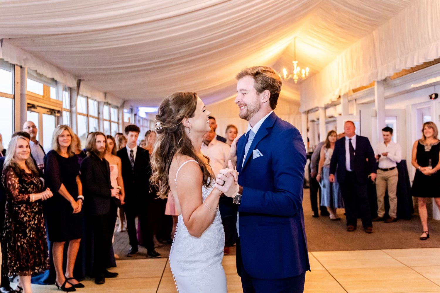 Wedding reception dance floor with guests celebrating under draped white fabric ceiling.
