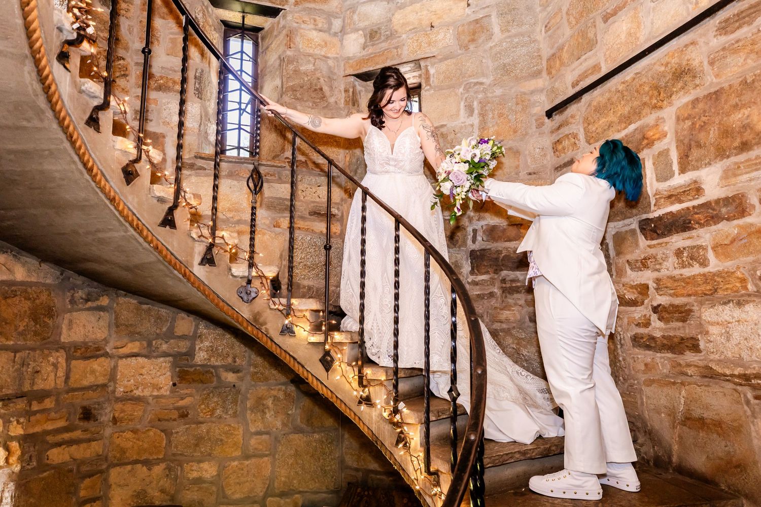 A couple poses on a historic spiral stone staircase during their wedding photoshoot.
