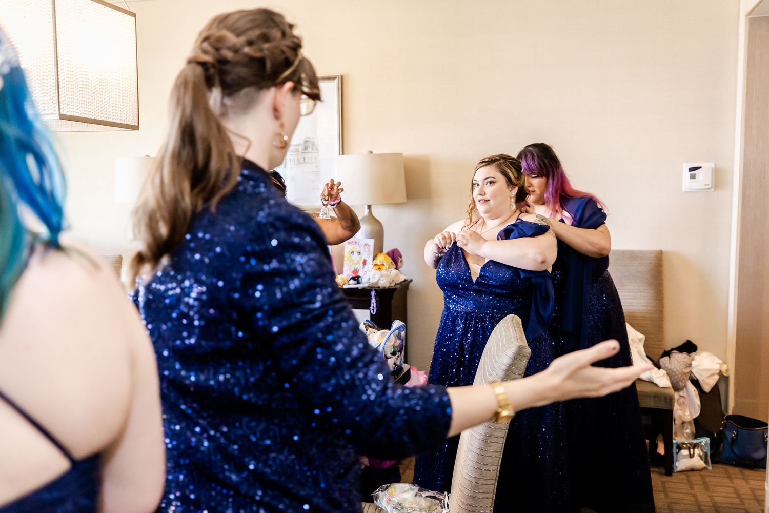 Wedding party in sparkly blue dresses celebrating in preparation room.