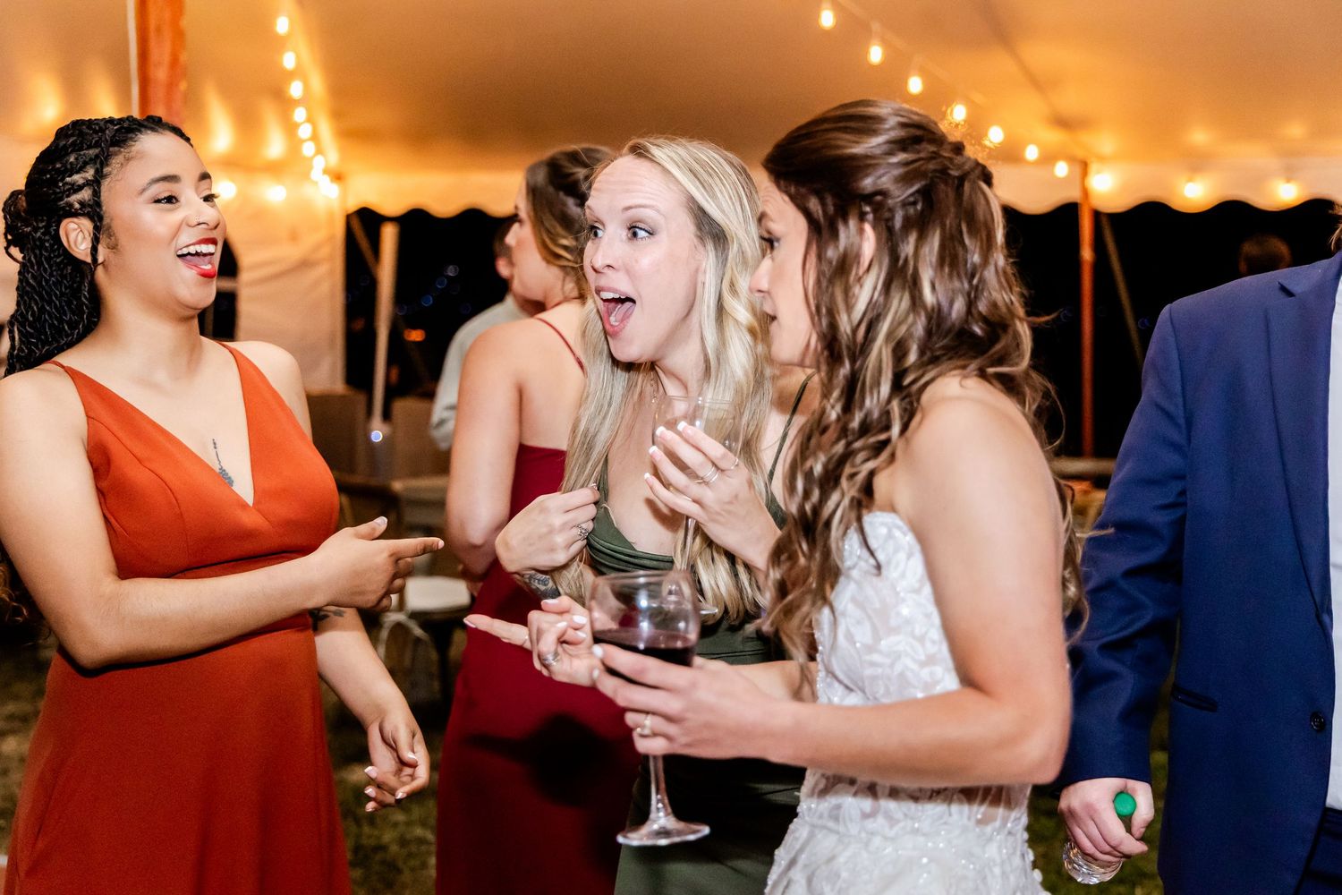 Wedding guests laughing and celebrating with champagne glasses during an evening reception.