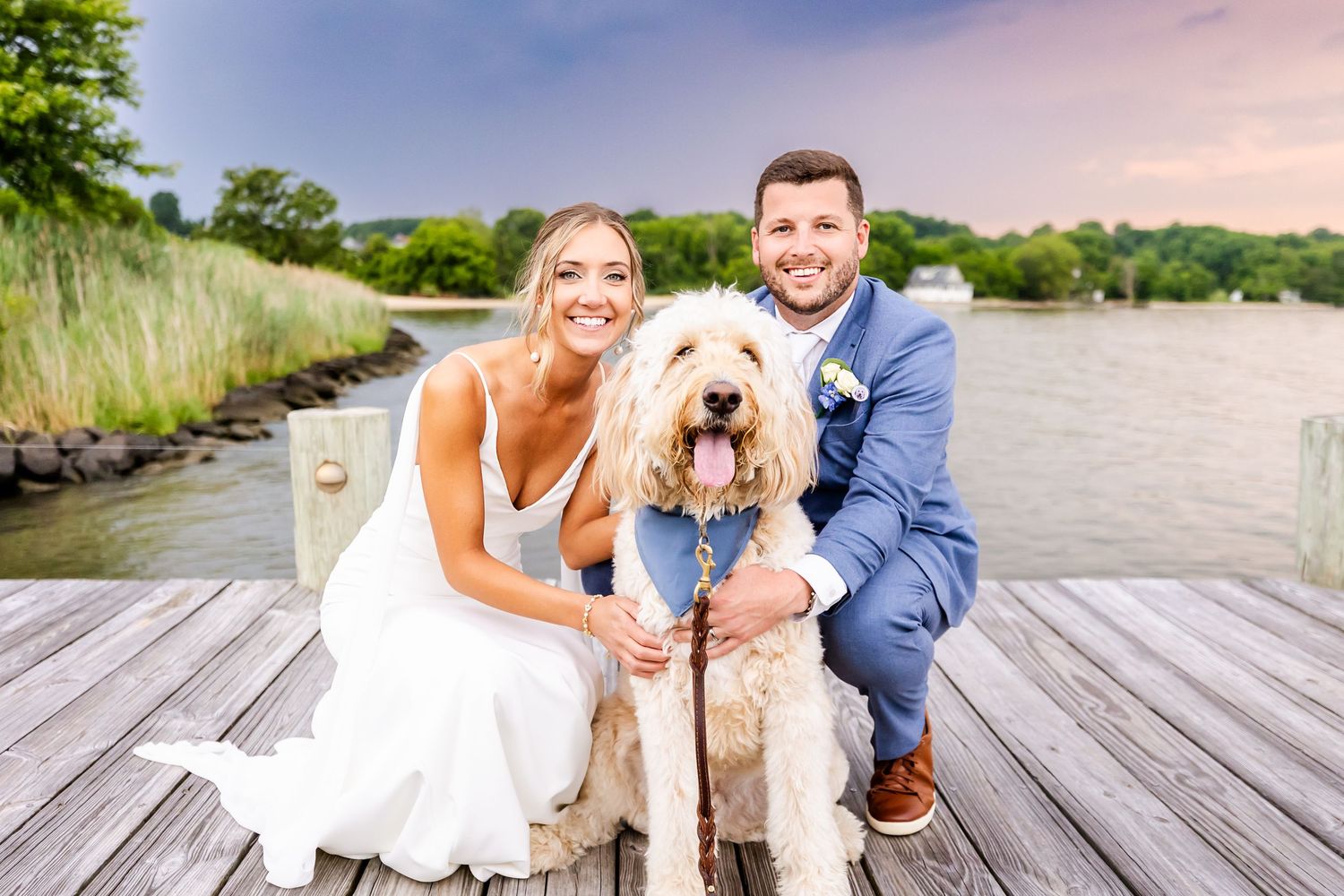 Couple shares joyful moments on a lakeside dock surrounded by nature during their summer wedding photoshoot.