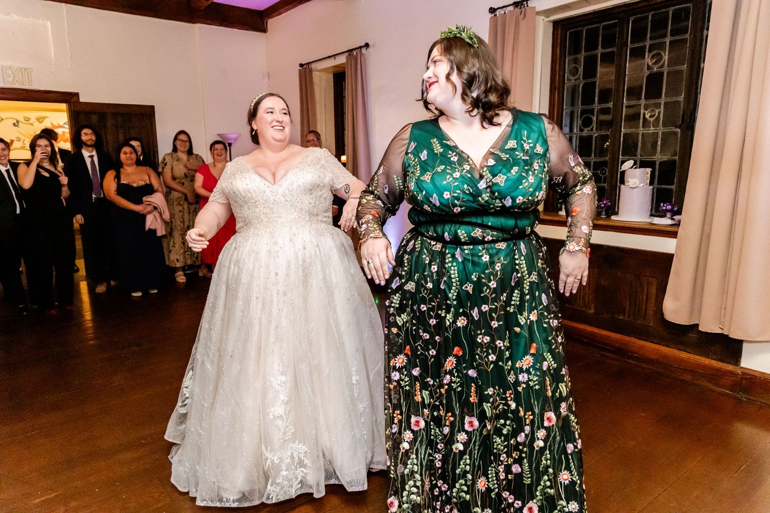 Two wedding attendees dancing together on a wooden floor during reception celebrations.