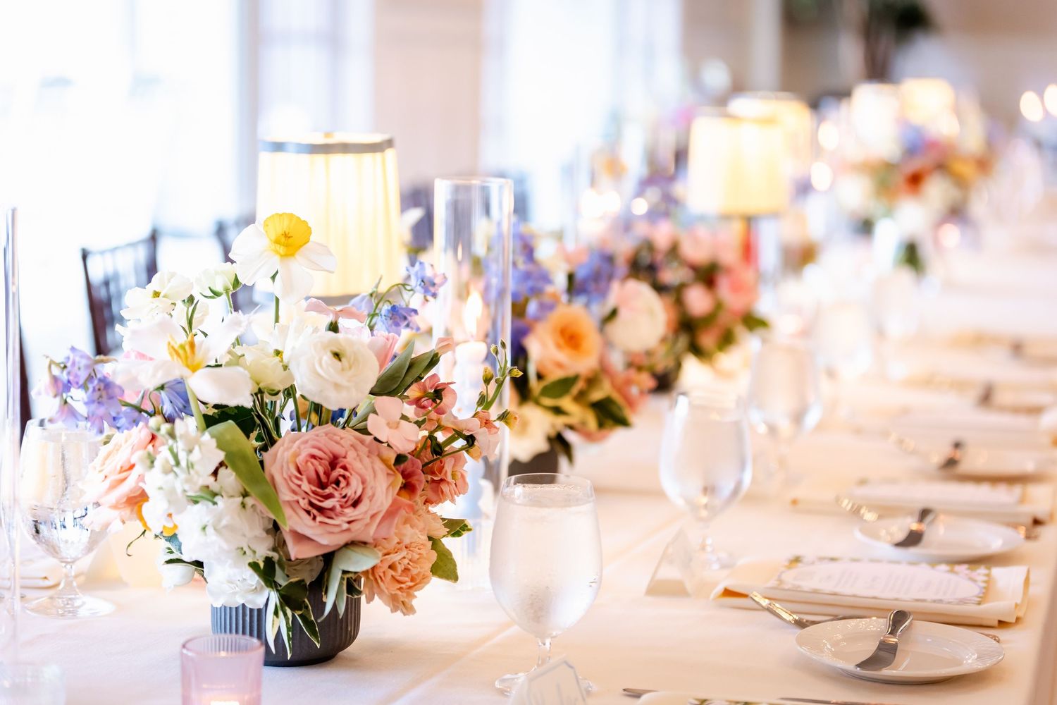 Elegant wedding table setting with pink and white floral centerpieces and crystal glassware.