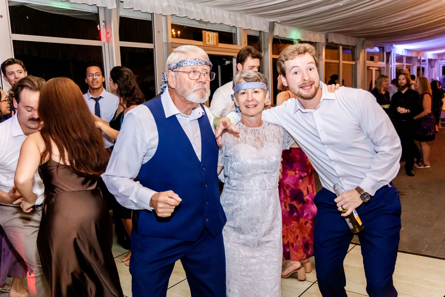 Wedding guests dance and celebrate on the dance floor during an evening reception under draped fabric decor.