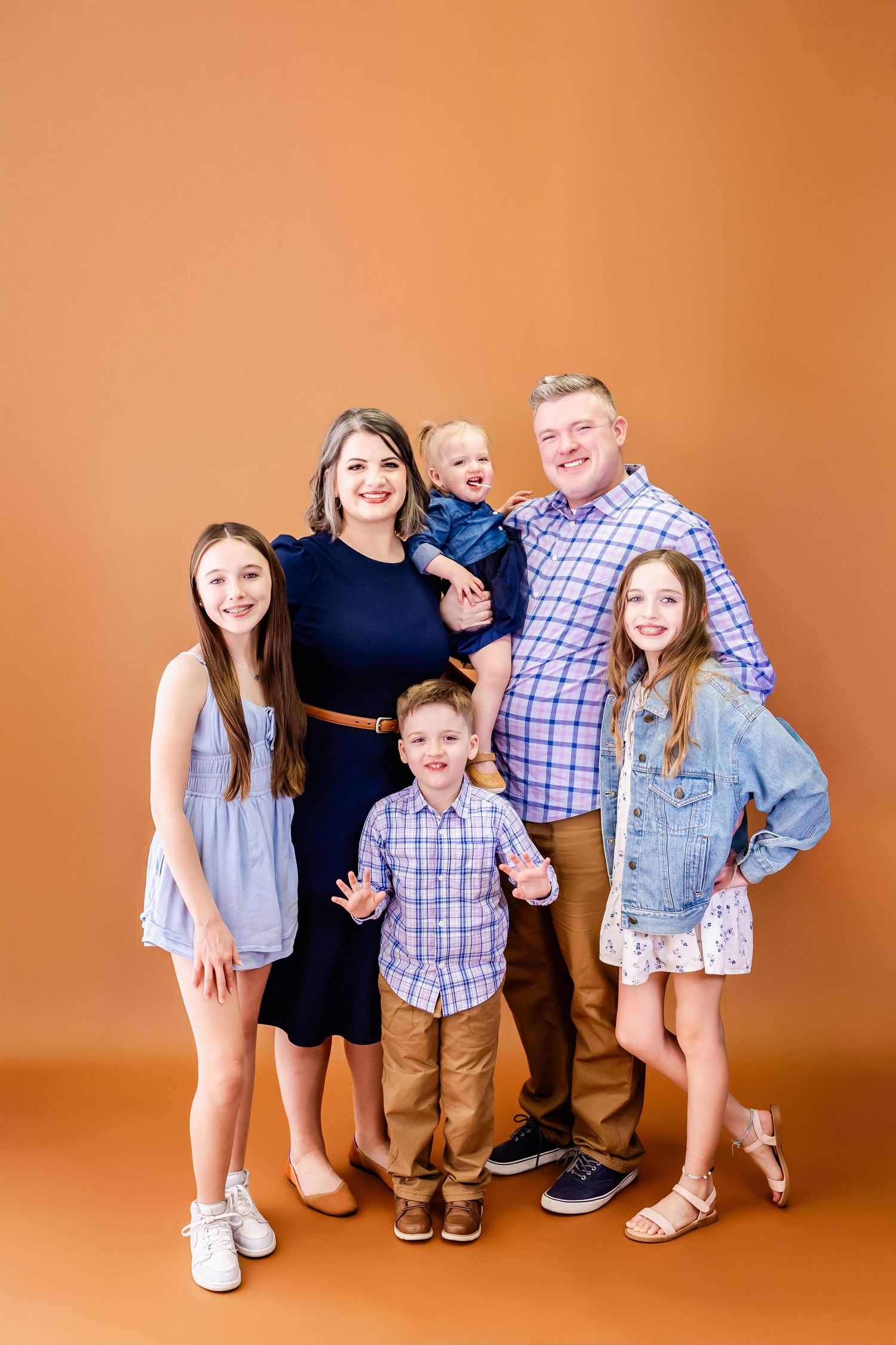 Energetic family photo sequence showing fun poses and expressions on orange backdrop.