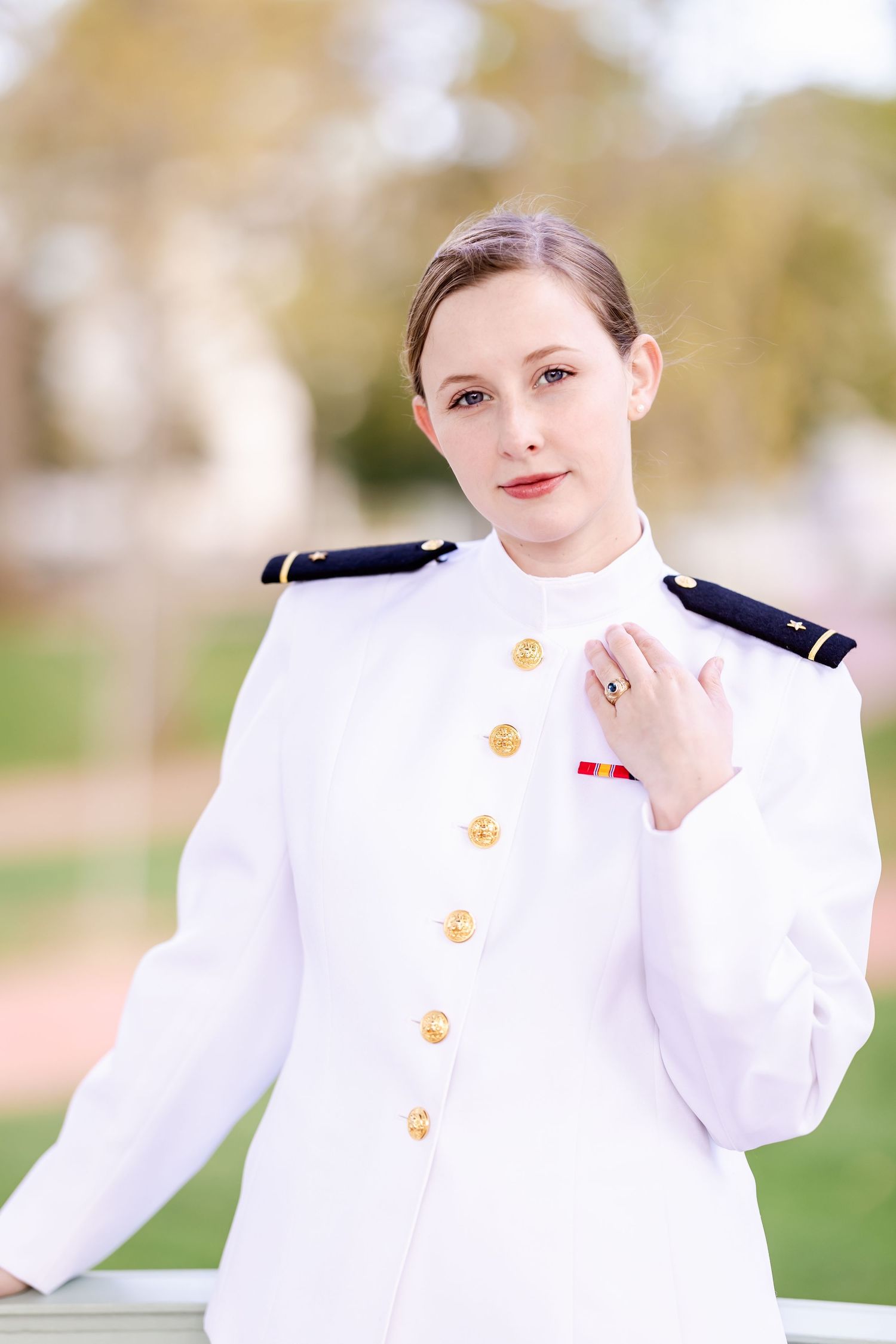 Naval officer in crisp white uniform with gold buttons poses for formal portrait.