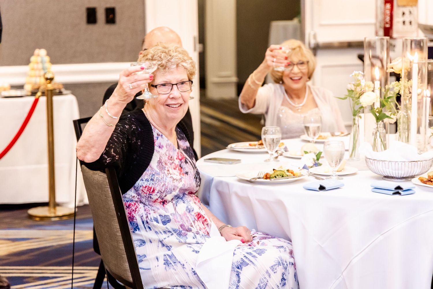 Wedding reception guests seated at decorated tables in banquet hall.