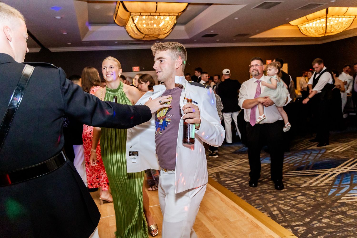 Wedding celebration in a ballroom with warm lighting and dancing guests.