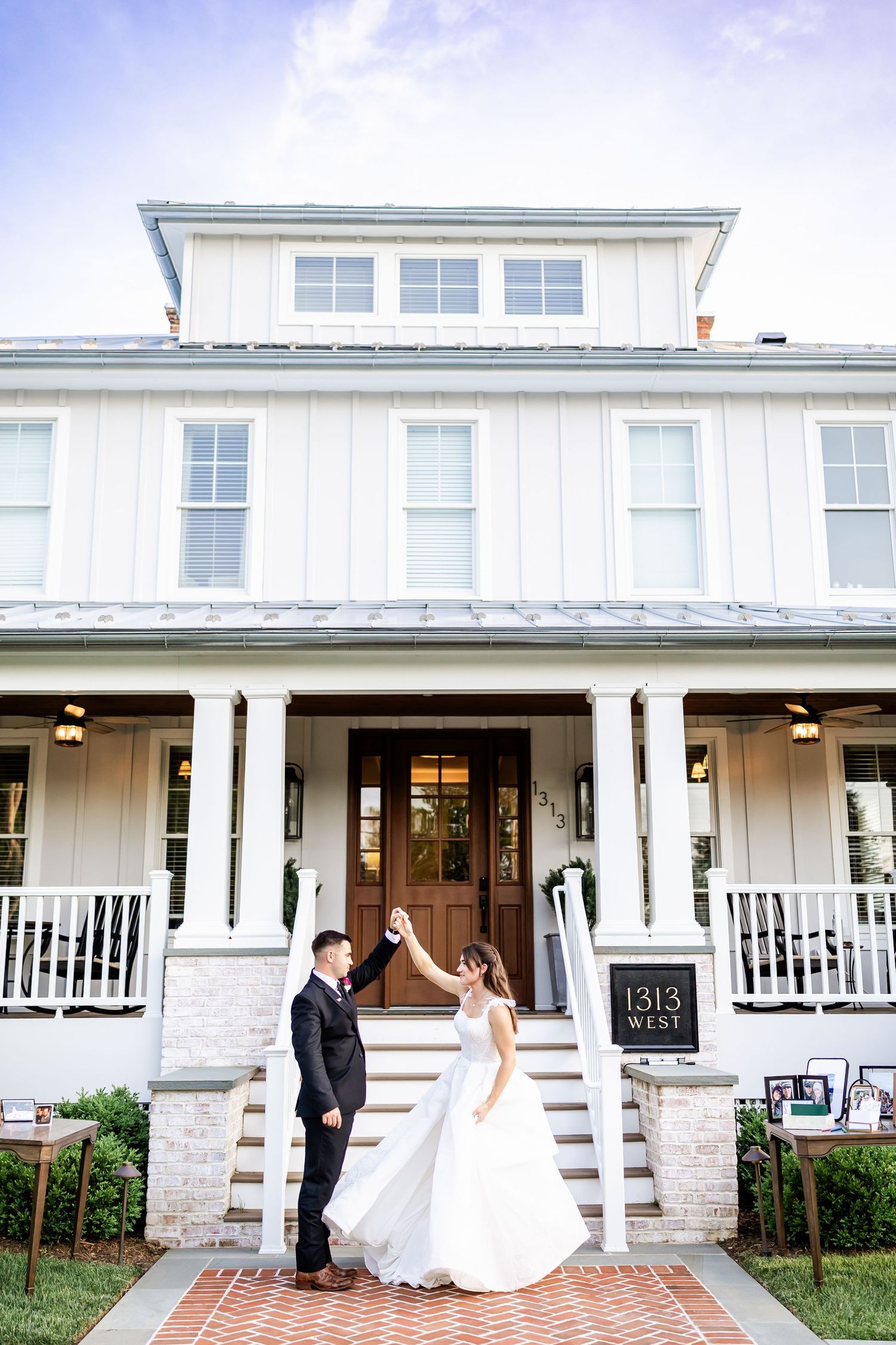 Elegant white farmhouse style venue with stone accents and columns for a wedding celebration.