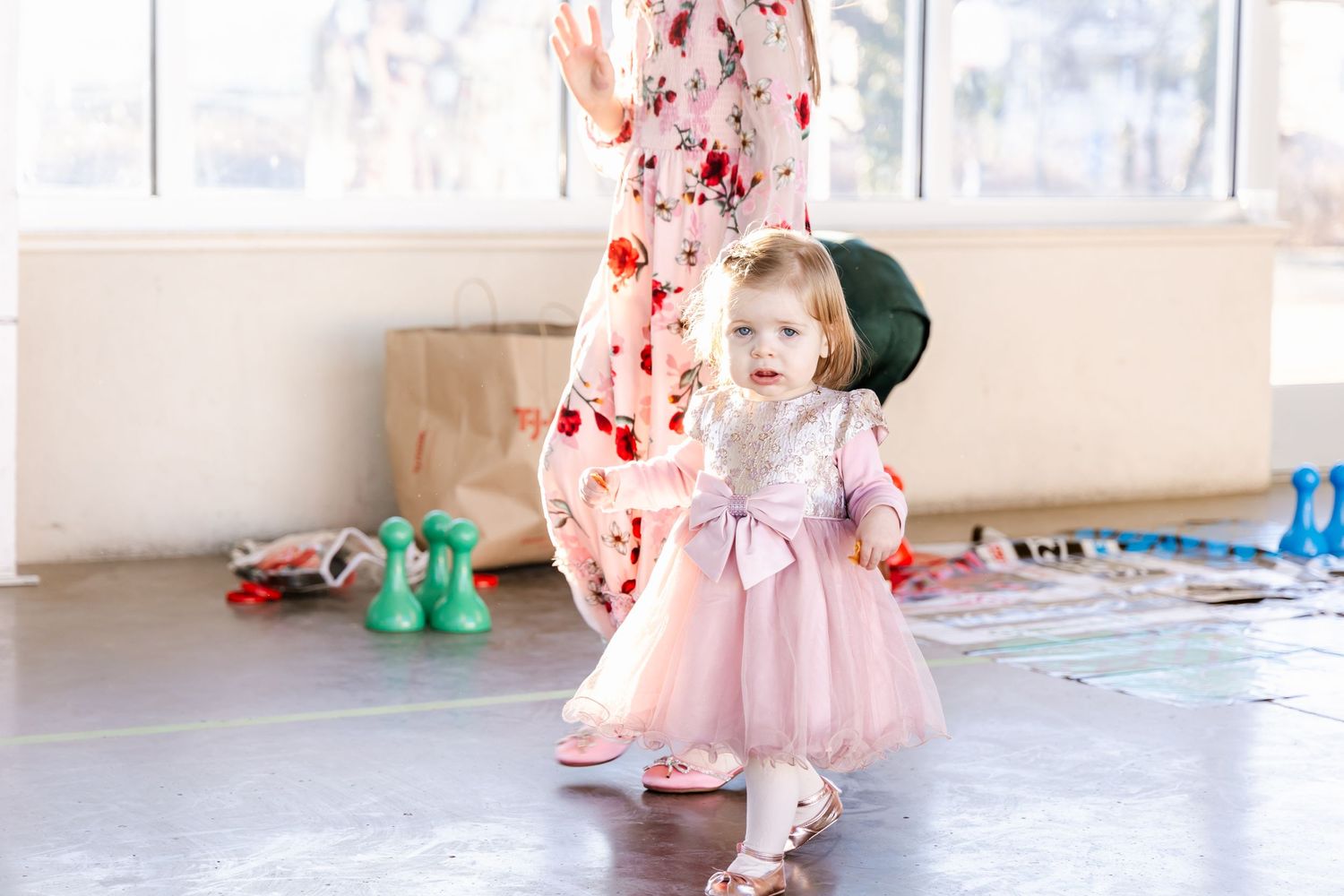 A small child in a pink tulle dress twirls on a dance floor.