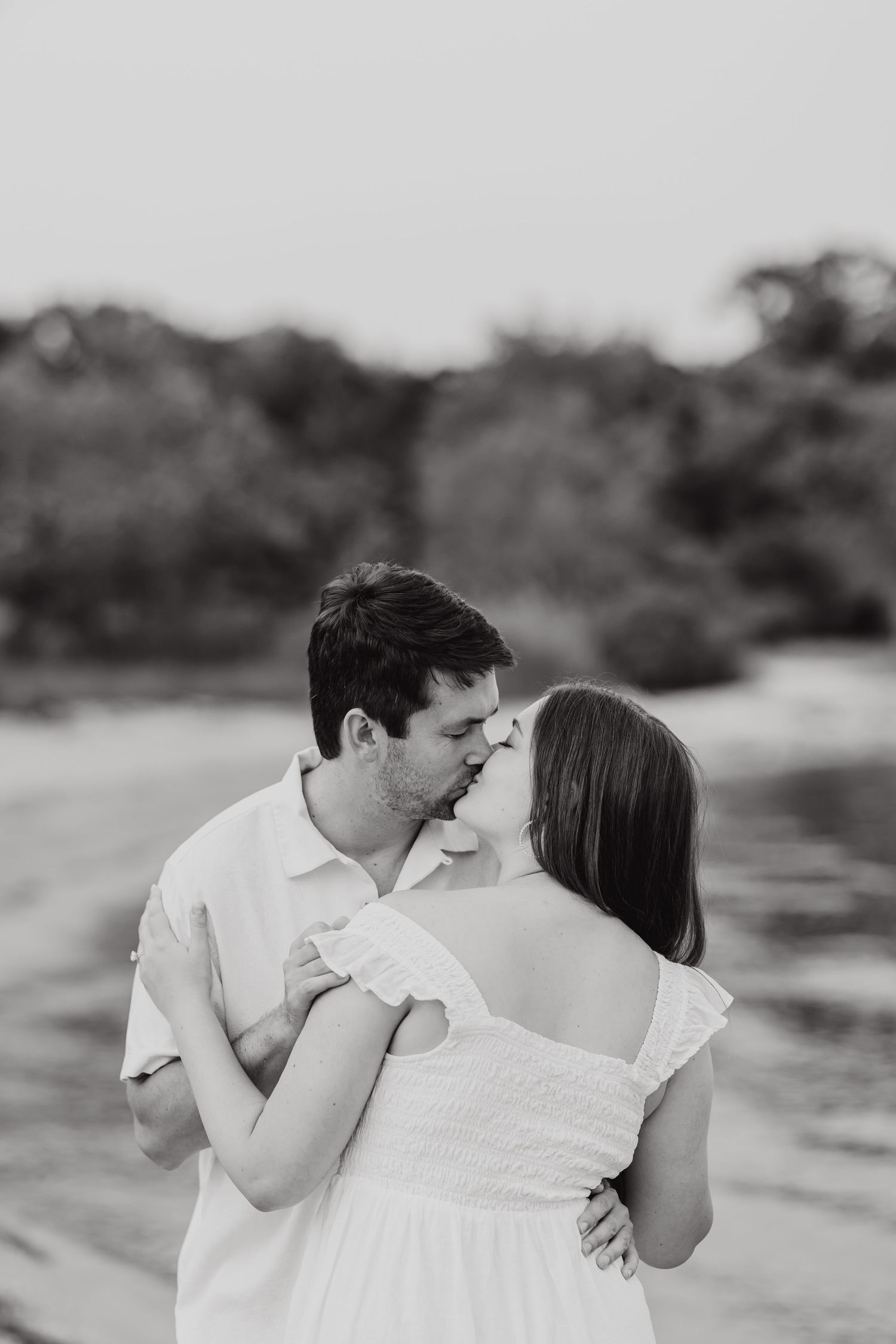 A black and white photo series shows a couple embracing lovingly outdoors.