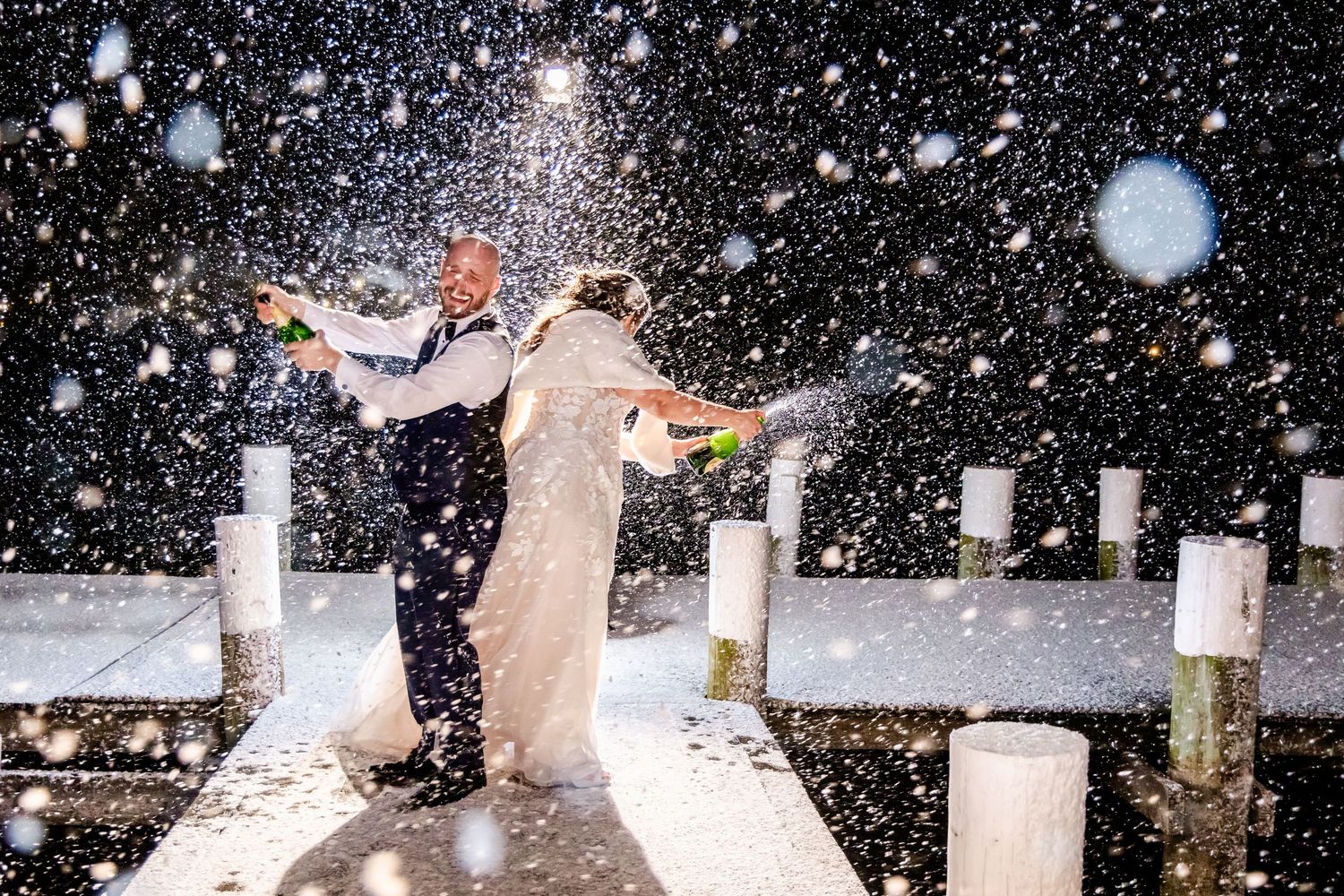 People enjoying a snowy day throwing snowballs at each other during winter at night with lights illuminating the scene.