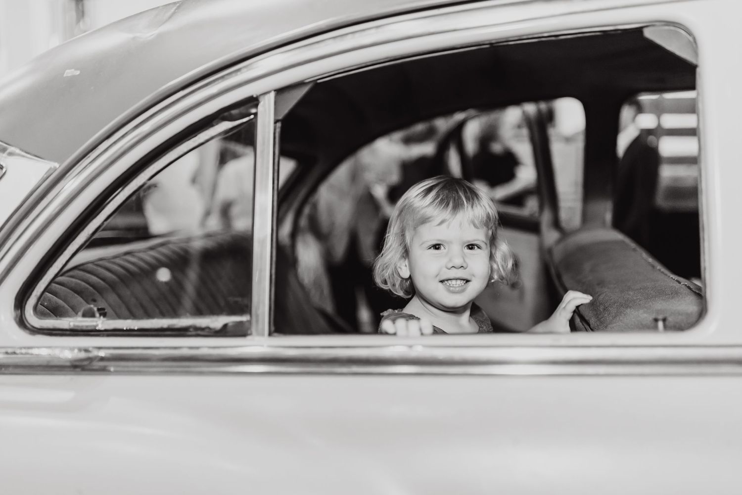 Vintage car window frames child passenger in black and white photography.