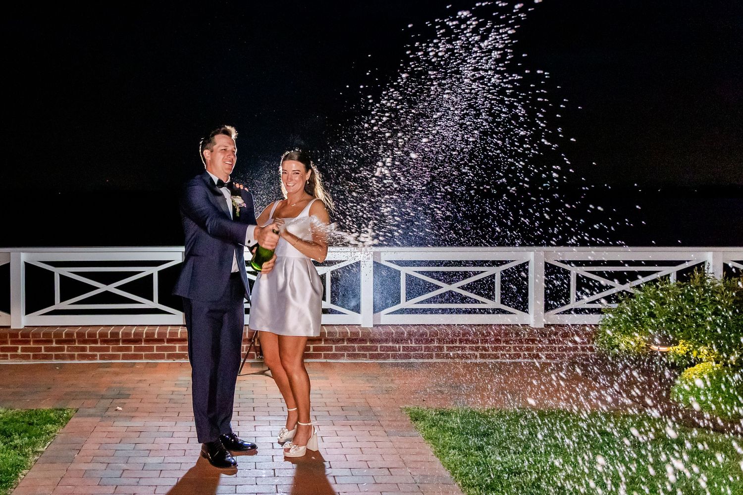 Wedding celebration with champagne spraying in the air during sunset at an outdoor venue.