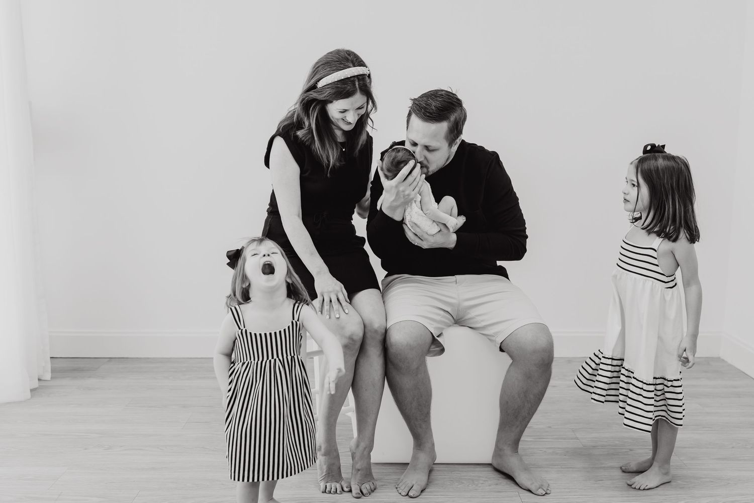 Family photography session in progress showing candid moments in a bright white studio space.